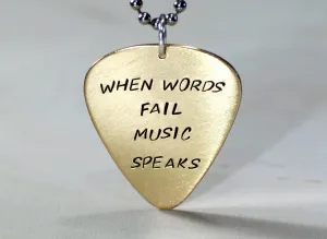 Bronze guitar pick necklace stamped with When words fail music speaks